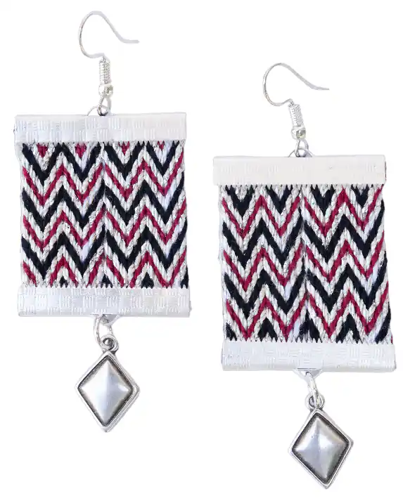 A pair of custom handmade woven dangle earrings by Ergastini, featuring the traditional Cretan "Path of Love" chevron pattern in black, deep red, and white, finished with a small silver diamond-shaped charm.